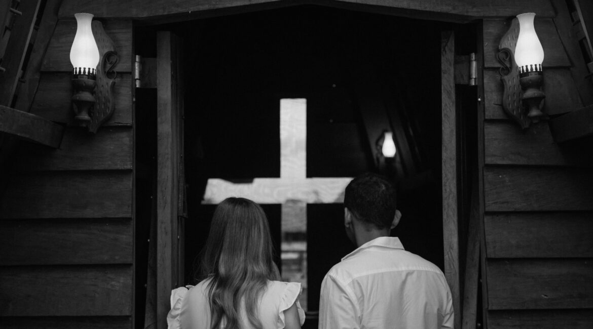 Couple seen from behind entering a church with a cross in Paragominas, Brazil.